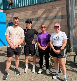 Four people standing outside with bikes
