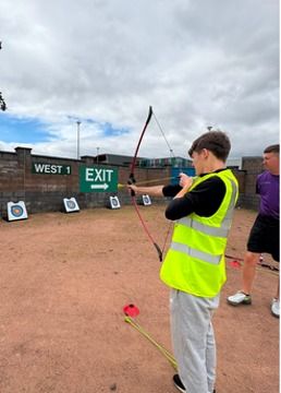 A person in a high-visibility jacket practising archery